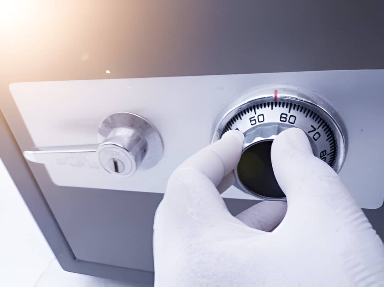 A person's hand wearing a glove is opening the security number on a money safe box