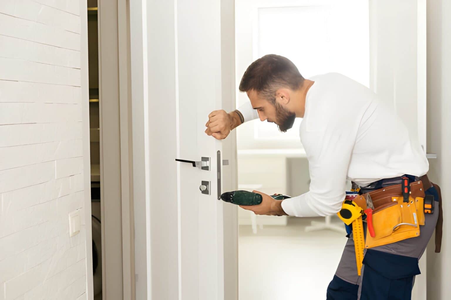 Good looking man working as handyman and fixing a door lock in a house entrance